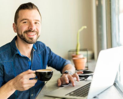 Man sitting at a laptop with a coffee - Life Skills Group Image