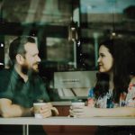 A man and woman facing each other in a coffee shop window - Relatives & Friends Programme Image