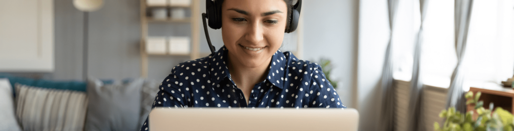 Person smiling sitting on front of a laptop