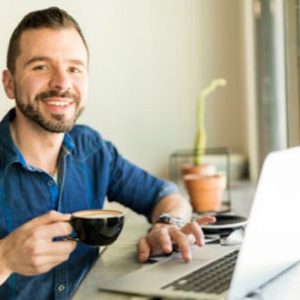 Man sitting at a laptop with a coffee - Life Skills Group Image